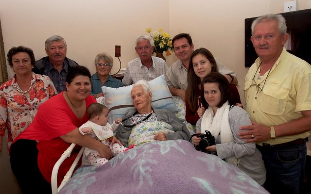 Kinders, kleinkinders, agter-kleinkinders en agter-agter-kleinkind staan bankvas agter Tannie Rens Fourie tydens haar verjaardag